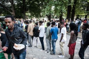 Migrants queuing in a square in Italy
